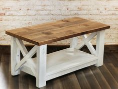 a wooden table sitting on top of a hard wood floor next to a brick wall