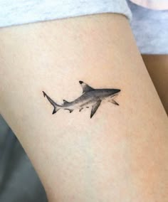 a small tattoo of a shark on the leg, it's black and white