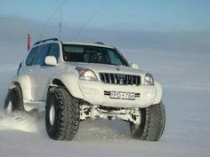 a white four wheel drive vehicle driving through the snow