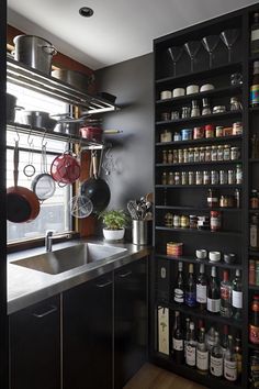 a kitchen with pots and pans hanging from the wall next to a sink in front of a window