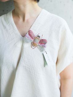 a woman wearing a white shirt with a pink butterfly on it's back and a tag attached to her neck