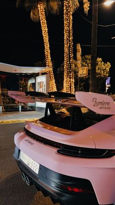 a pink sports car parked in front of a building with lights on it's roof