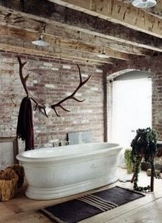 a large bath tub sitting in the middle of a room next to a brick wall