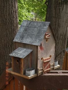 a bird house is on top of a wooden fence in front of a large tree