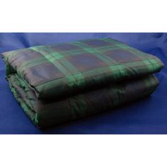 a green and black plaid blanket on top of a blue bed sheet with two pillows