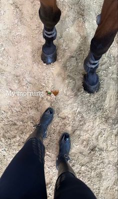 two people standing in the dirt with their feet up and one person wearing blue boots