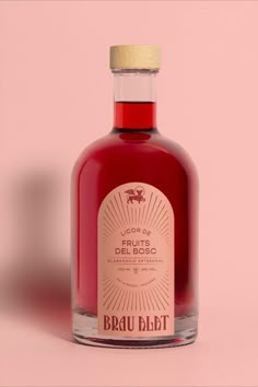 a bottle of red liquid on a pink background