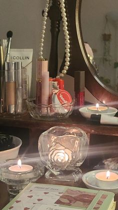 a table with candles and other items sitting on it's counter top in front of a mirror