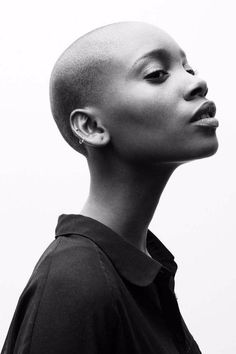 a black and white photo of a woman with shaved hair looking up at the sky