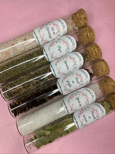 five spice jars filled with different types of spices and herbs on a pink tablecloth