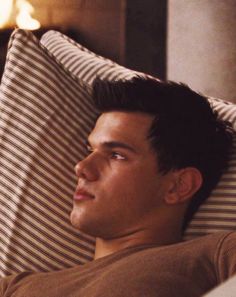 a man laying in bed with his head on the pillow and looking off into the distance