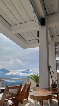 an outdoor patio with wooden chairs and table on the balcony overlooking the mountains in the distance