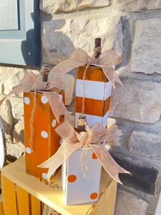 two orange and white wine bottles sitting on top of a wooden crate next to a stone wall