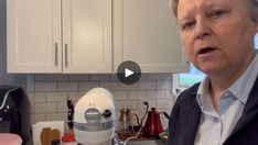 a man standing in front of a kitchen counter next to a blender and mixer