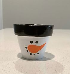 a white cup with a black lid and a snowman face on the inside is sitting on a table