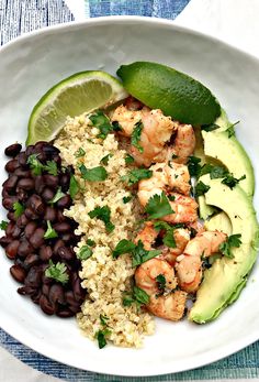 a white plate topped with rice, black beans and avocado next to lime wedges