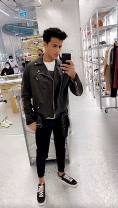 a young man is taking a selfie with his phone in a clothing store while wearing black and white sneakers