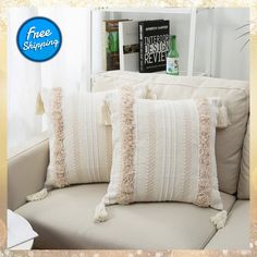 two white pillows sitting on top of a couch next to a book shelf filled with books