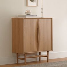 a wooden cabinet sitting on top of a hard wood floor next to a white wall