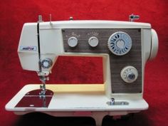 an old sewing machine is sitting on a red carpeted surface with buttons and knobs