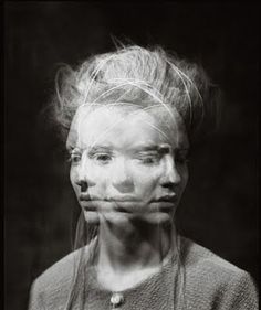 a black and white photo of a woman's face with hair blowing in the wind