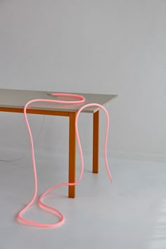 a table that has some kind of neon light on it and is sitting in front of a white wall