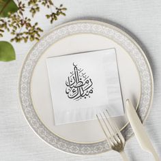 a white plate topped with a napkin next to a fork and knife on top of a table