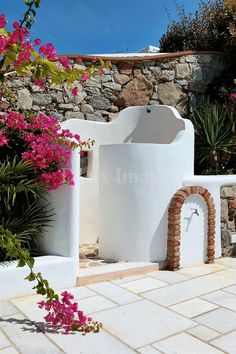 a white building with pink flowers growing out of it's doorways and walls