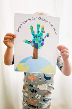 a young child holding up a poster with the words small hands can change the world