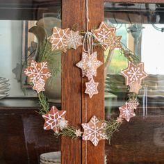 a wreath made out of gingerbread cookies hanging from a wooden door with snowflakes on it