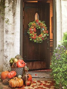 the front door is decorated for fall with pumpkins and other autumn decorating items