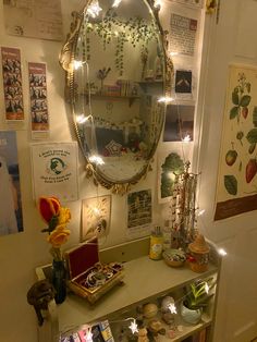 a mirror and some lights on a wall above a table with flowers in vases