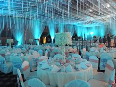 a room filled with lots of tables covered in white and blue cloths