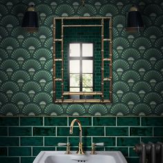 a bathroom sink under a mirror in front of a green wall with art deco tiles