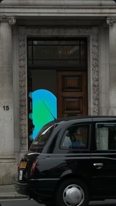 a black car driving past a tall building