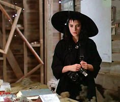 a woman wearing a witches hat and holding a camera in front of a table with other items on it