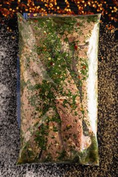 a bag filled with meat and vegetables on top of a granite counter next to a pile of spices