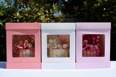 three pink and white boxes with flowers in them