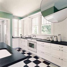 a black and white checkered floor in a kitchen with an oval mirror on the wall