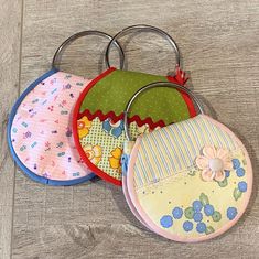 three baby bibs are sitting on a wooden floor with metal rings attached to them