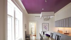 a dining room with purple painted ceiling and white walls