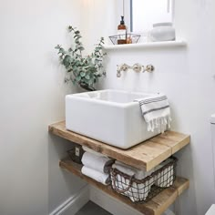 a white sink sitting on top of a wooden shelf next to a toilet in a bathroom