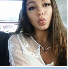 a woman sticking her tongue out in the back seat of a car while wearing a white shirt