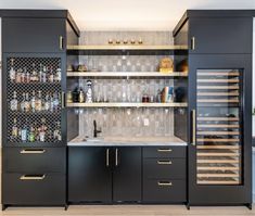 a kitchen with black cabinets and gold trim on the doors, wine racks in the back