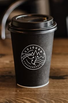 a black coffee cup sitting on top of a wooden table