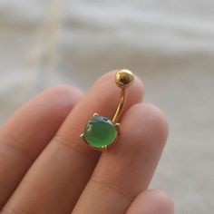 a close up of a person's hand holding a ring with a green stone