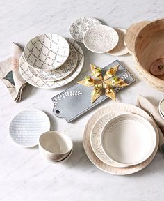 a table topped with lots of white plates and bowls on top of a marble counter