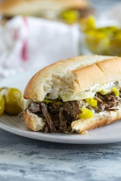 a close up of a sandwich on a plate with olives and bread in the background