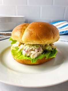 a chicken salad sandwich sitting on top of a white plate