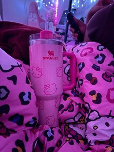 a pink hello kitty cup sitting on top of a bed